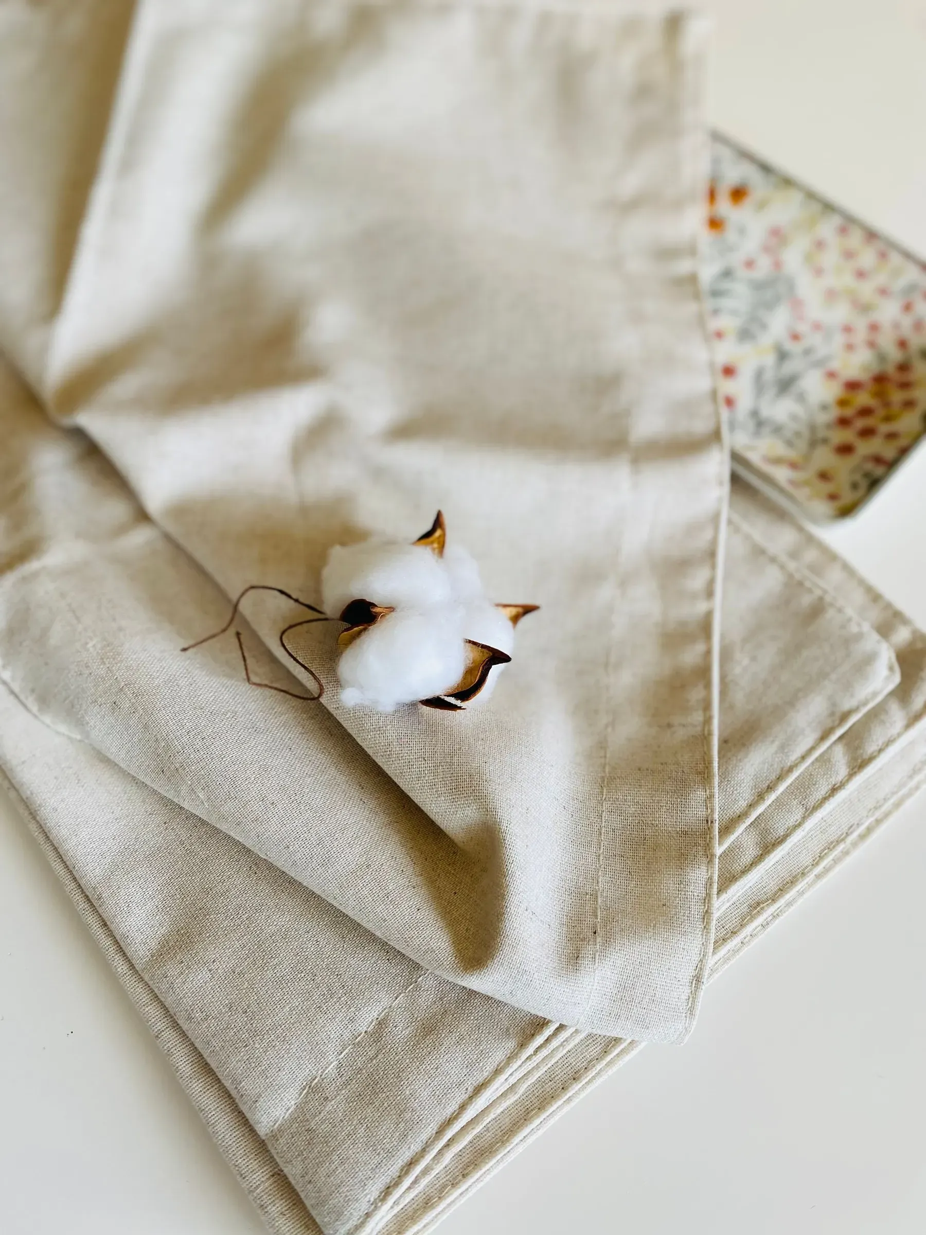 A raw cotton boll resting on folded unbleached cotton